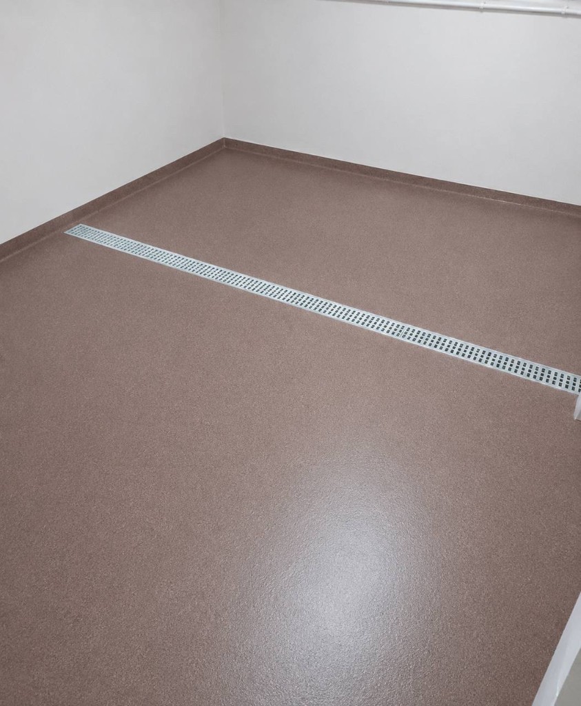Piso em metacrilato (MMA) em Porto - revestimento contínuo terracota com rodapé sanitário e grelha de drenagem, Rev-Tek Portugal